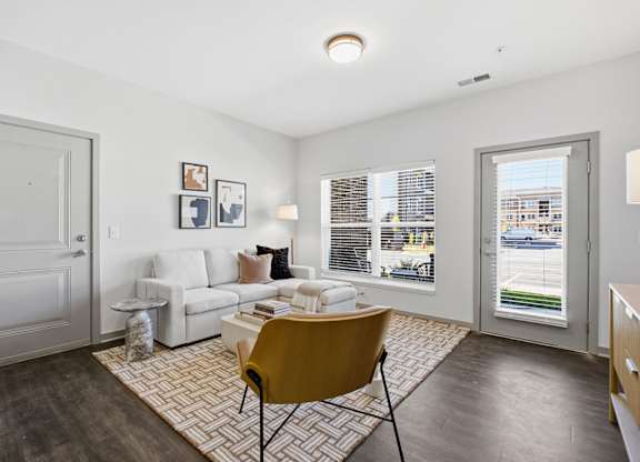 A living room with a yellow chair and a white sofa.