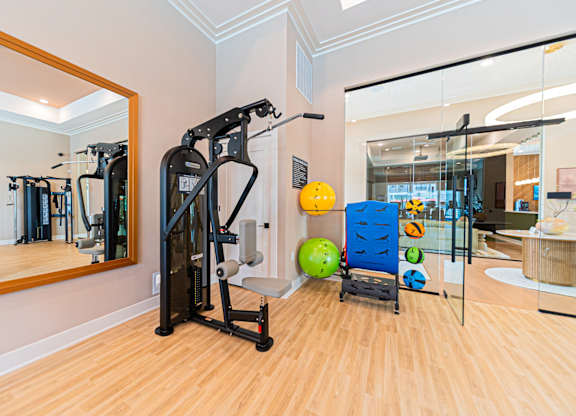 A gym with a mirror, exercise equipment, and a ball.