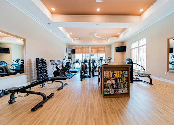 A gym with a variety of equipment including treadmills, weights, and exercise machines.