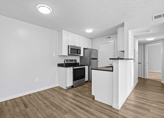 A kitchen with white cabinets and a wooden floor.