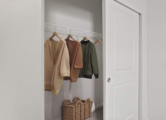 Clothes hanging on a rack in a closet.