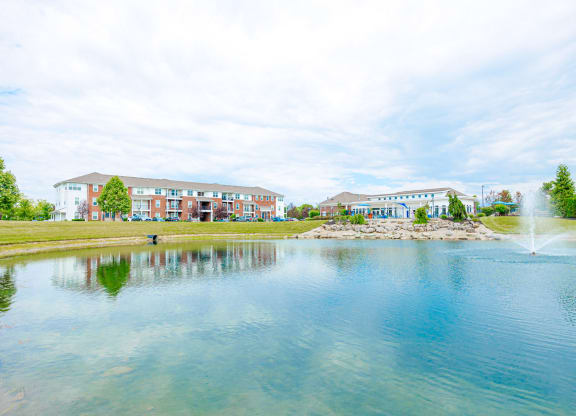 a pond with a fountain in front of a building