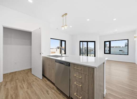 A modern kitchen with wooden floors and stainless steel appliances.