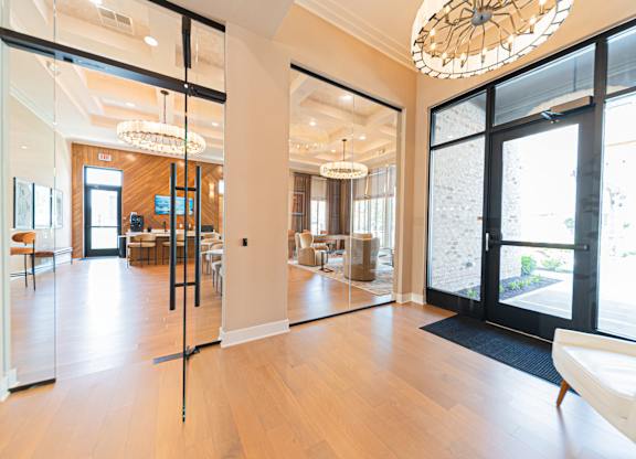 A large, open living room with a wooden floor and a glass door leading to a balcony.