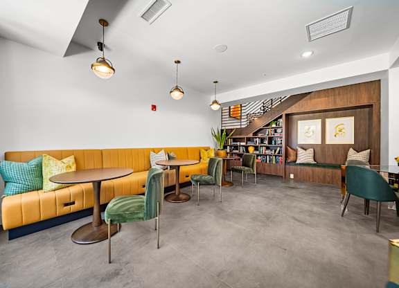 A room with a yellow couch and a grey floor.