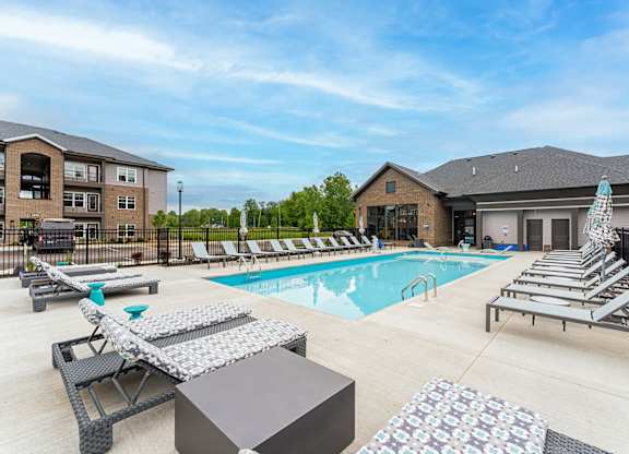 A pool area with sun loungers and a building in the background.