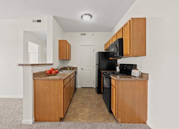 A kitchen with black appliances and wooden cabinets.