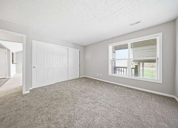 A room with a carpeted floor and a window with blinds.