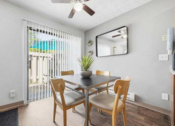 A dining room with a table and chairs and a ceiling fan.