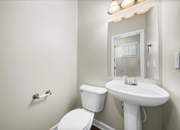 A white toilet sits next to a white sink in a bathroom.