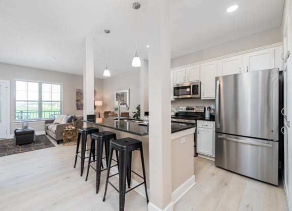 an open kitchen and living room with stainless steel appliances and bar stools