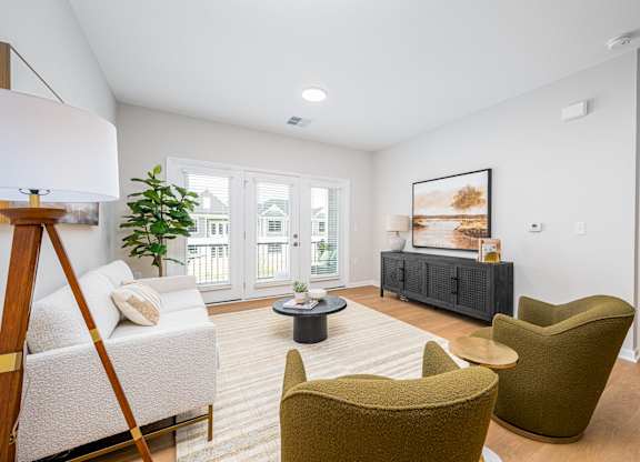 A living room with a white sofa, a green armchair, and a coffee table.