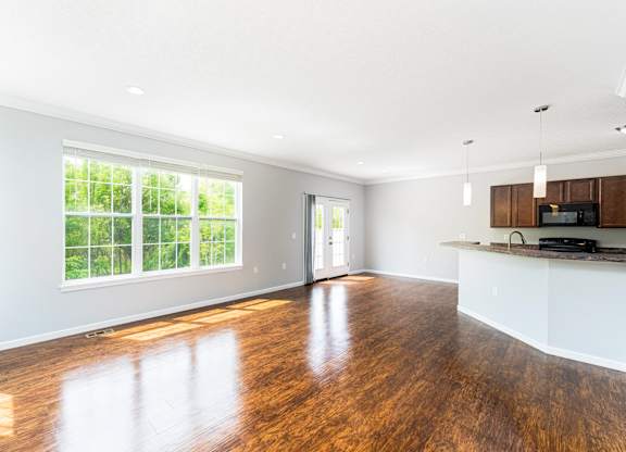 A spacious kitchen and living room with wooden floors and white walls.