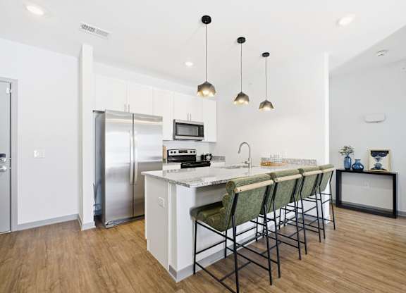 A kitchen with a white counter and green chairs.