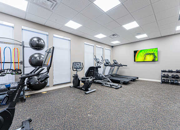 A gym with a variety of equipment including a stationary bike, treadmill, and weights.