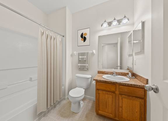 A bathroom with a toilet, sink, and shower.