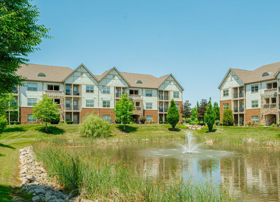 a pond with a fountain in front of an apartment building