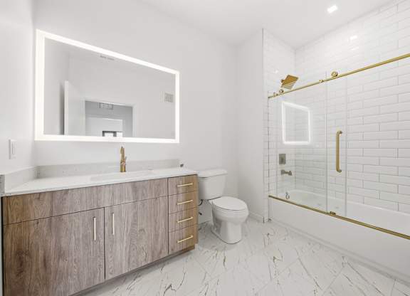 A white bathroom with a wooden vanity and a white toilet.