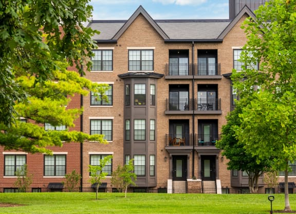 a brick apartment building with balconies and trees in front of it