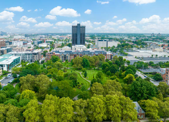 a cityscape with a tall building in the background and trees in the foreground