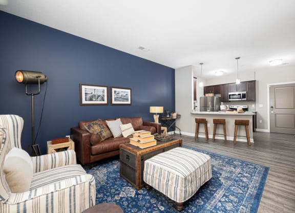 a living room with a couch and a chair in front of a kitchen