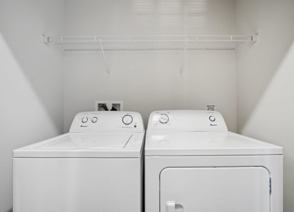 Two white washing machines in a small laundry room.