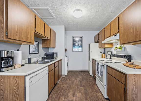 A kitchen with white appliances and wooden cabinets.