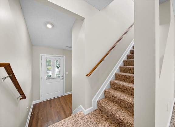 A staircase with a carpeted runner and wooden handrail.