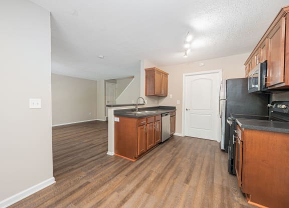 an empty kitchen with wood flooring and black appliances