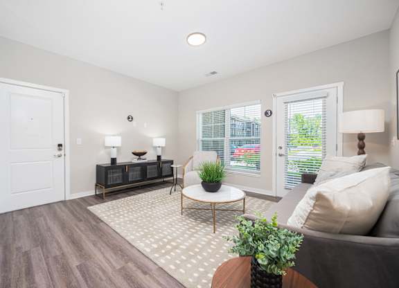 A living room with a grey couch, a wooden coffee table, and a white door.