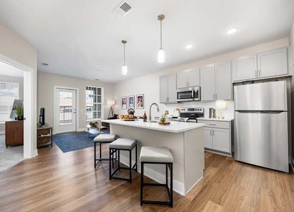 A modern kitchen with a bar stool and a refrigerator.