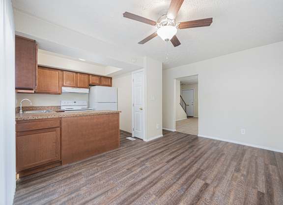 A room with a brown floor and a ceiling fan.