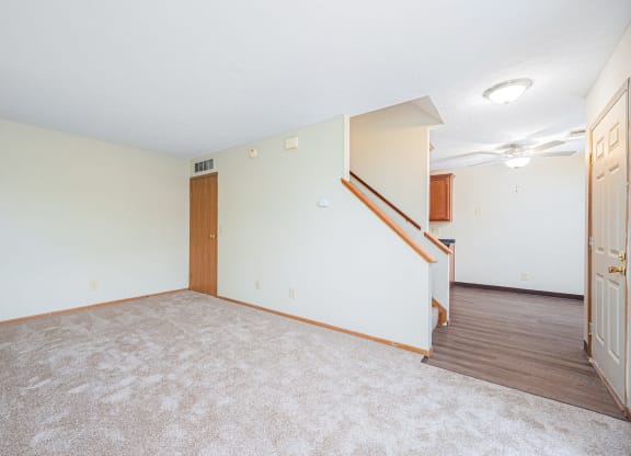 a living room with carpet and a door to a staircase
