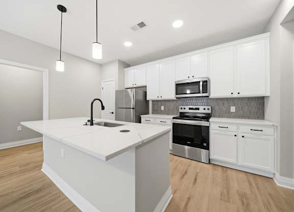 A kitchen with white cabinets and a large island.