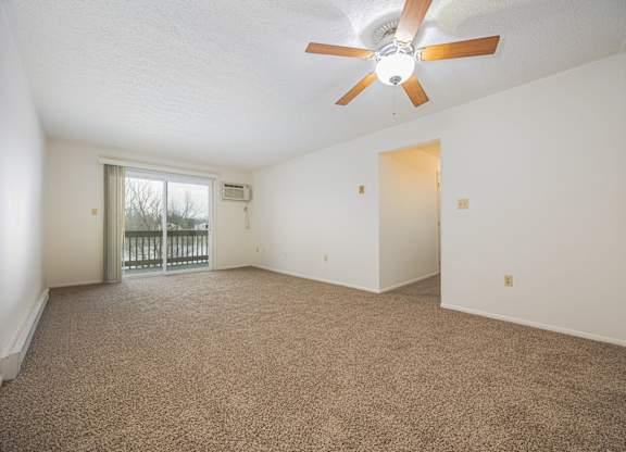 A room with a ceiling fan and carpeted floor.