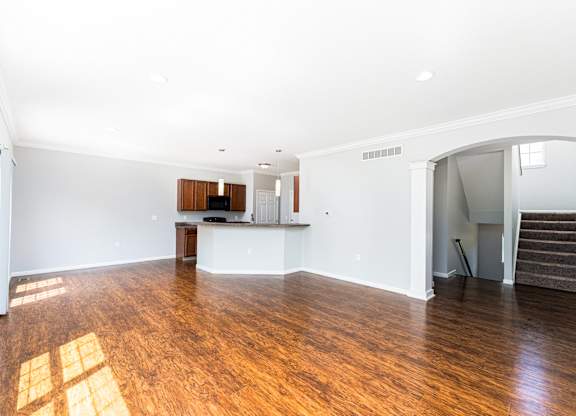 A large empty room with wooden floors and white walls.