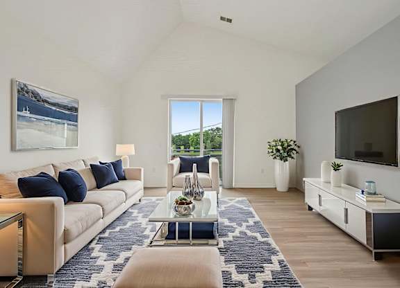 A living room with a large window and a painting of a beach scene on the wall.