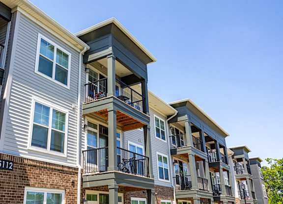 Apartment building with balconies and windows on a sunny day.