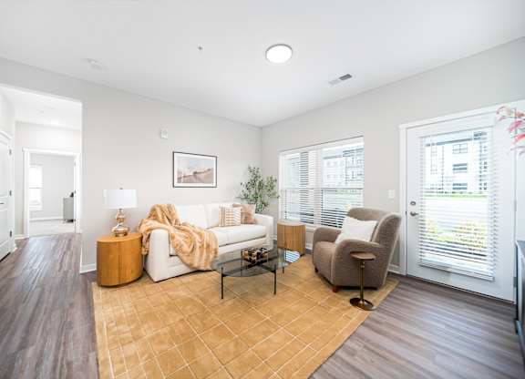 A living room with a white couch, a wooden coffee table, and a brown rug.