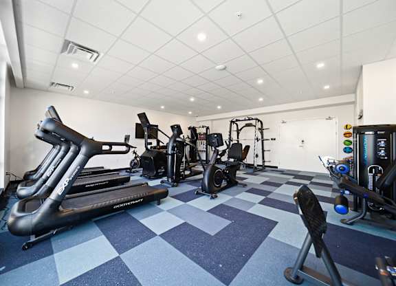 A gym with a variety of equipment including treadmills, weights, and exercise machines.