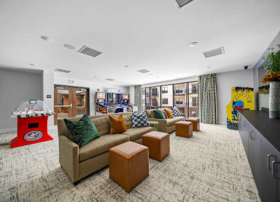 A room with a couch, a coffee table, and a gaming machine.