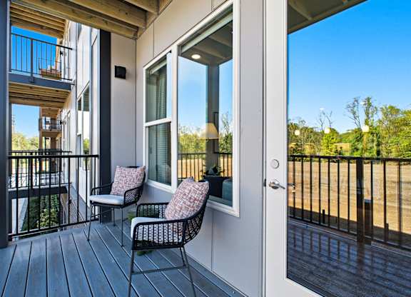 A balcony with a chair and a table with a cushion on it.