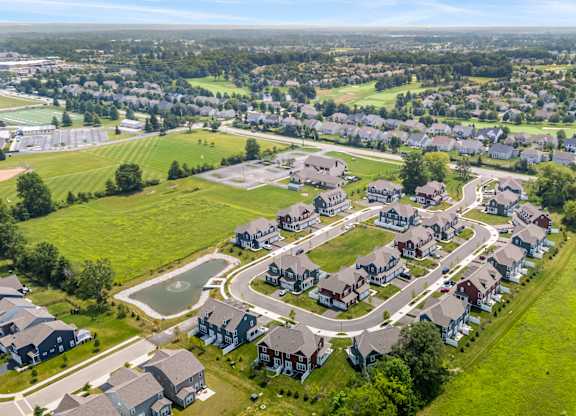 A bird's eye view of a residential neighborhood with houses and a pond.