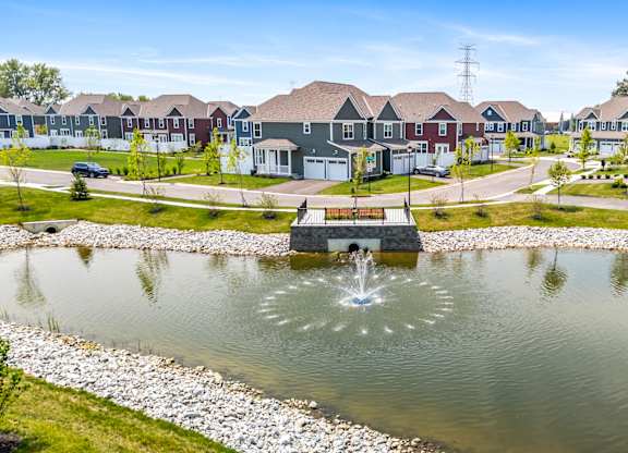 A pond with a fountain in the middle of a residential area.
