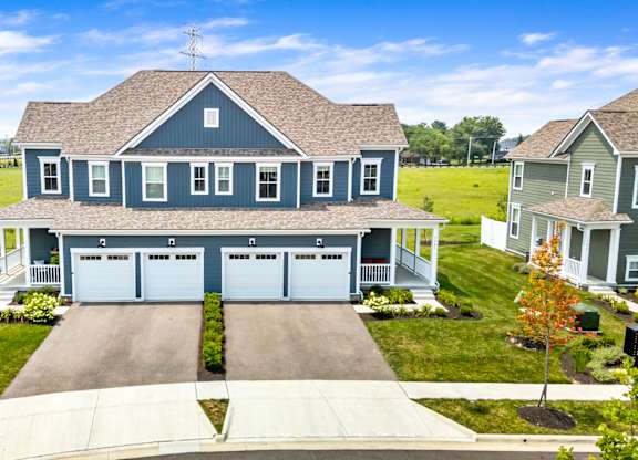 A large house with a grey roof and a garage with four doors.