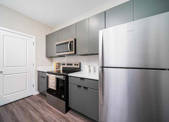 A kitchen with a stainless steel refrigerator, microwave, and oven