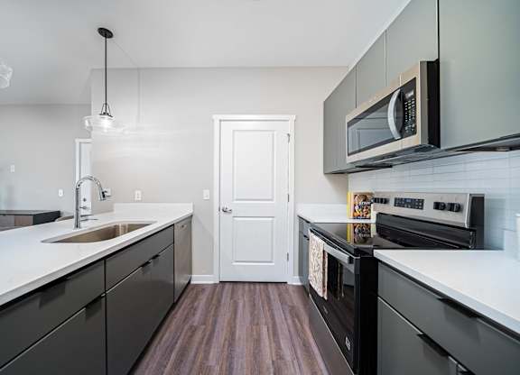 A modern kitchen with dark wood floors and white cabinetry.
