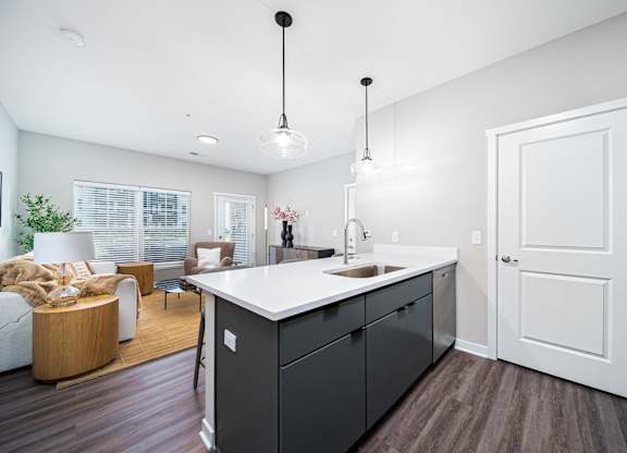 A modern kitchen with dark wood floors and white walls.