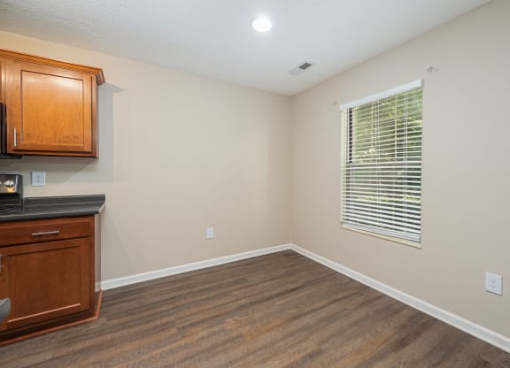 an empty living room with a window and a kitchen