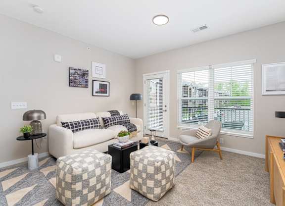 A living room with a couch, ottoman, and a chair.